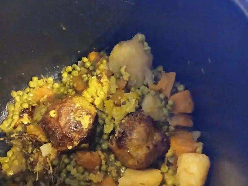 黑色炖锅里炖好的姜黄豌豆胡萝卜土豆肉丸