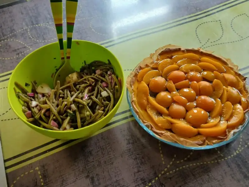 绿色沙拉碗里的红洋葱黄瓜四季豆沙拉，旁边是一个桃子挞